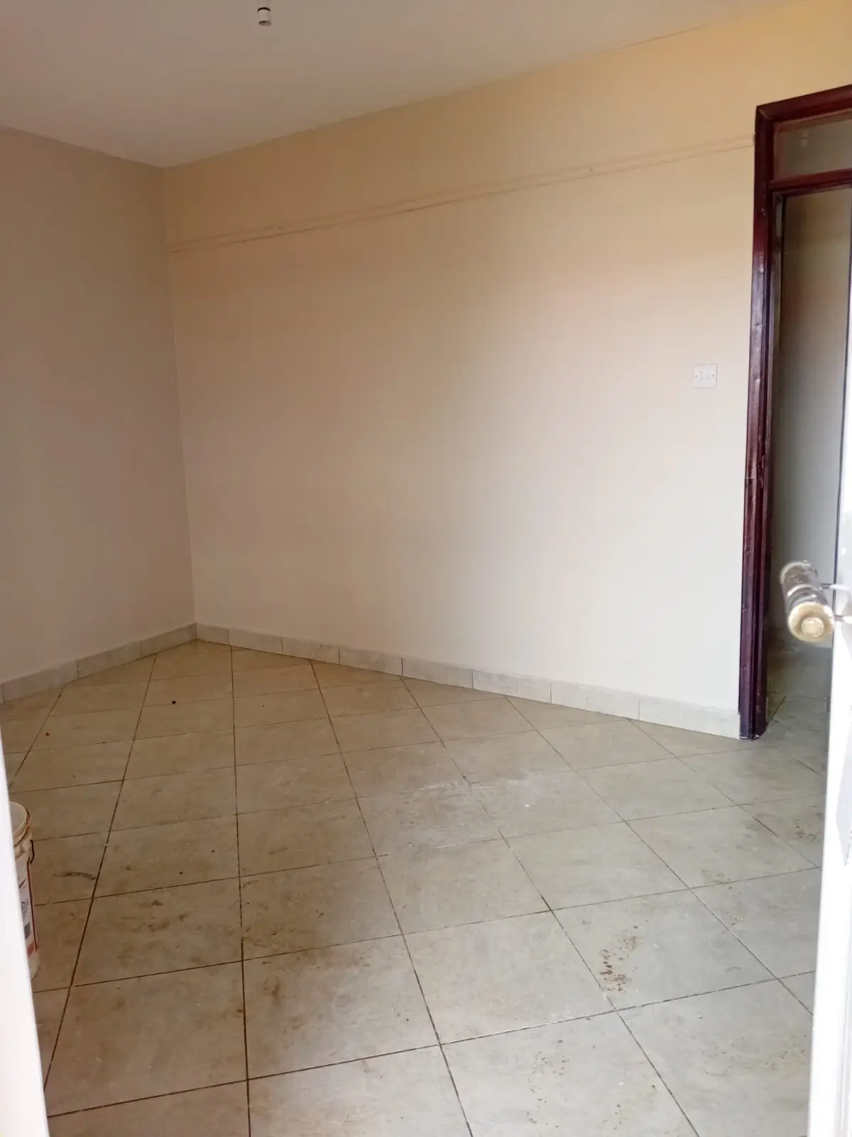 Empty bedroom with tiled floor and wooden door frame