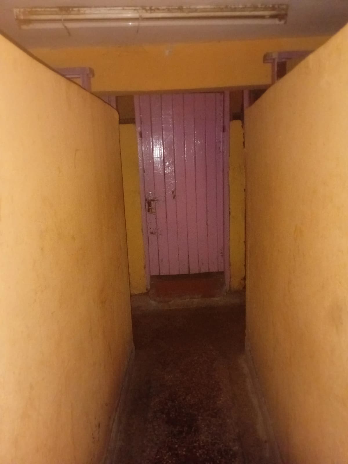 Narrow corridor with yellow walls and burgundy door
