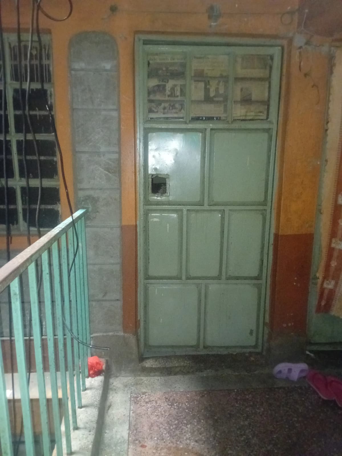 Building entrance hallway with green metal door and railing