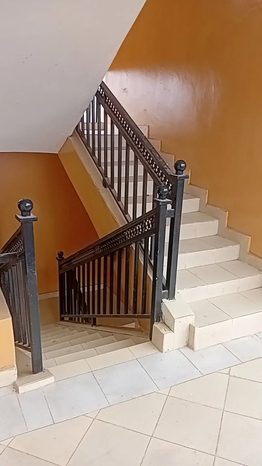 Internal staircase with black railing and cream tiles