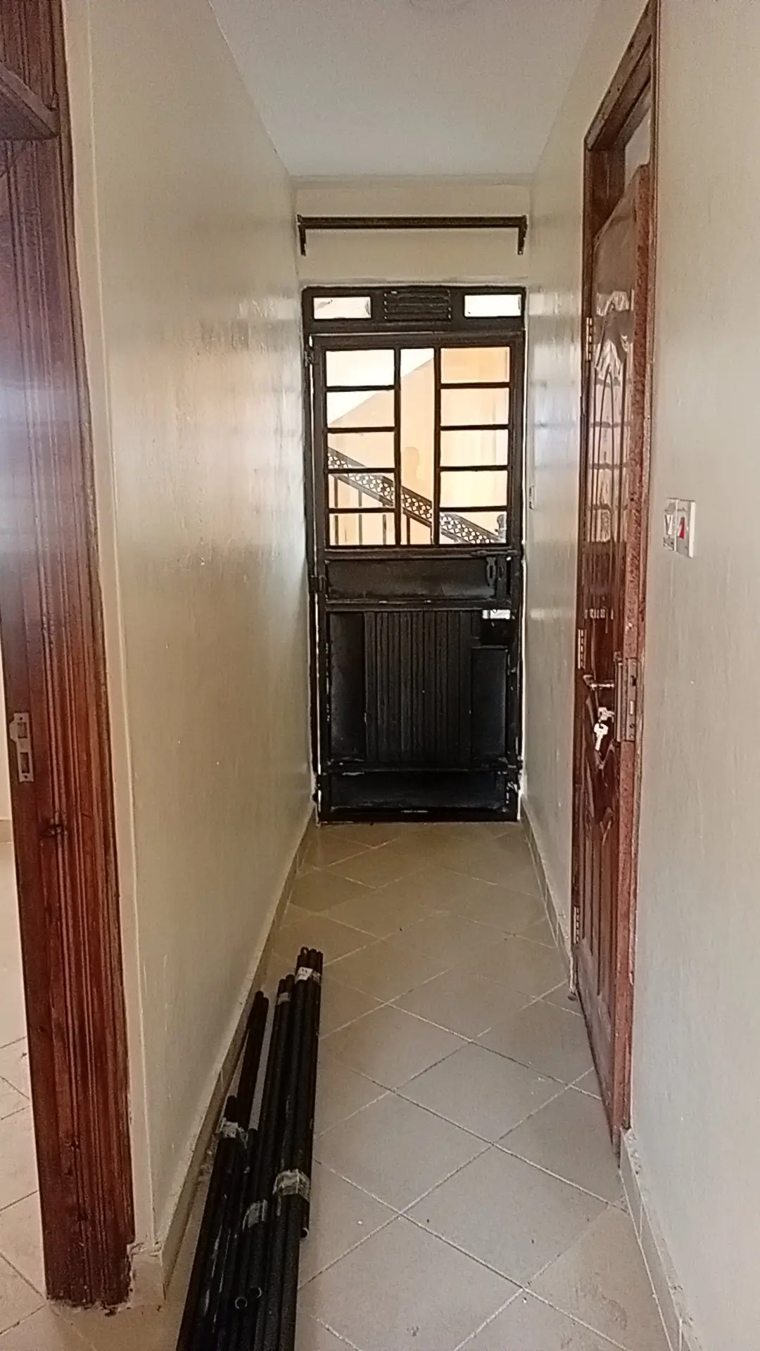 Narrow corridor with black door and wooden frame entrance