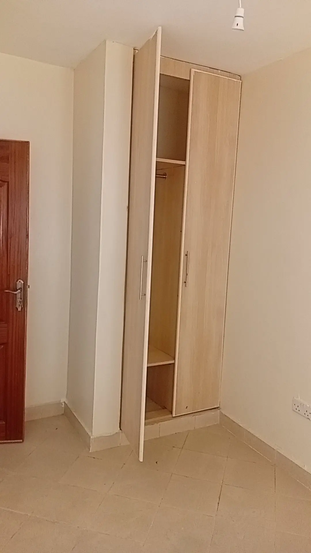 Empty bedroom with wooden wardrobe and red door