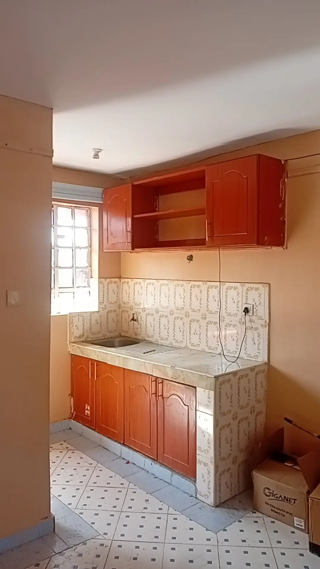 Compact kitchen with red cabinetry, patterned backsplash tile