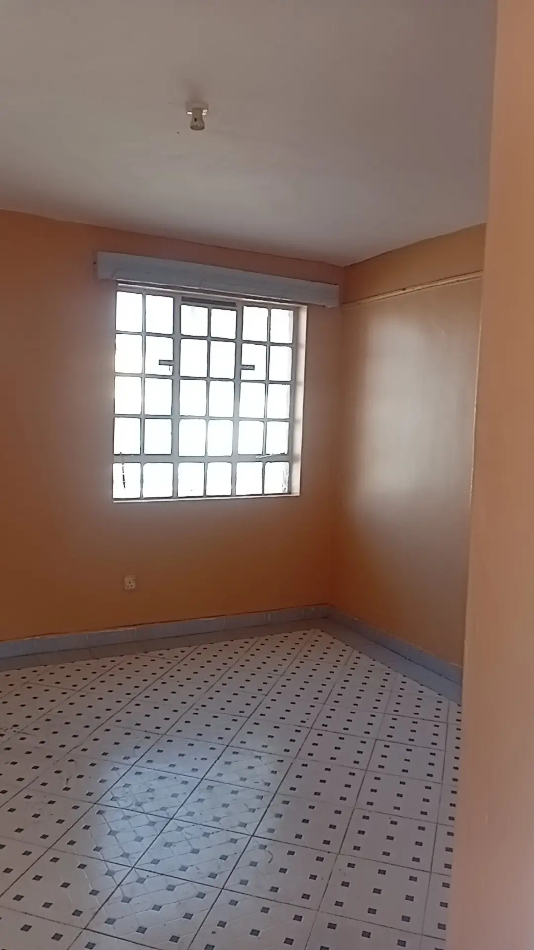 Empty bedroom with orange walls and tiled floor
