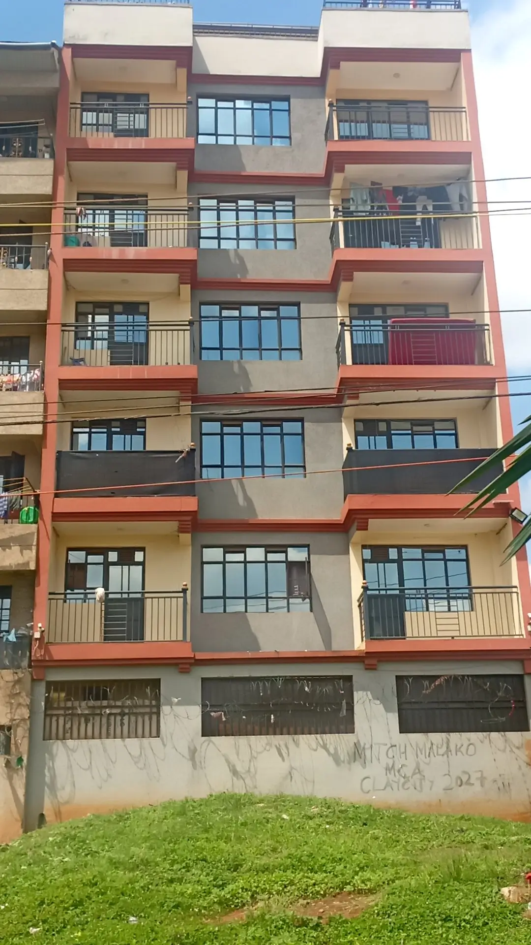 Multi-story residential building facade with red and beige trim