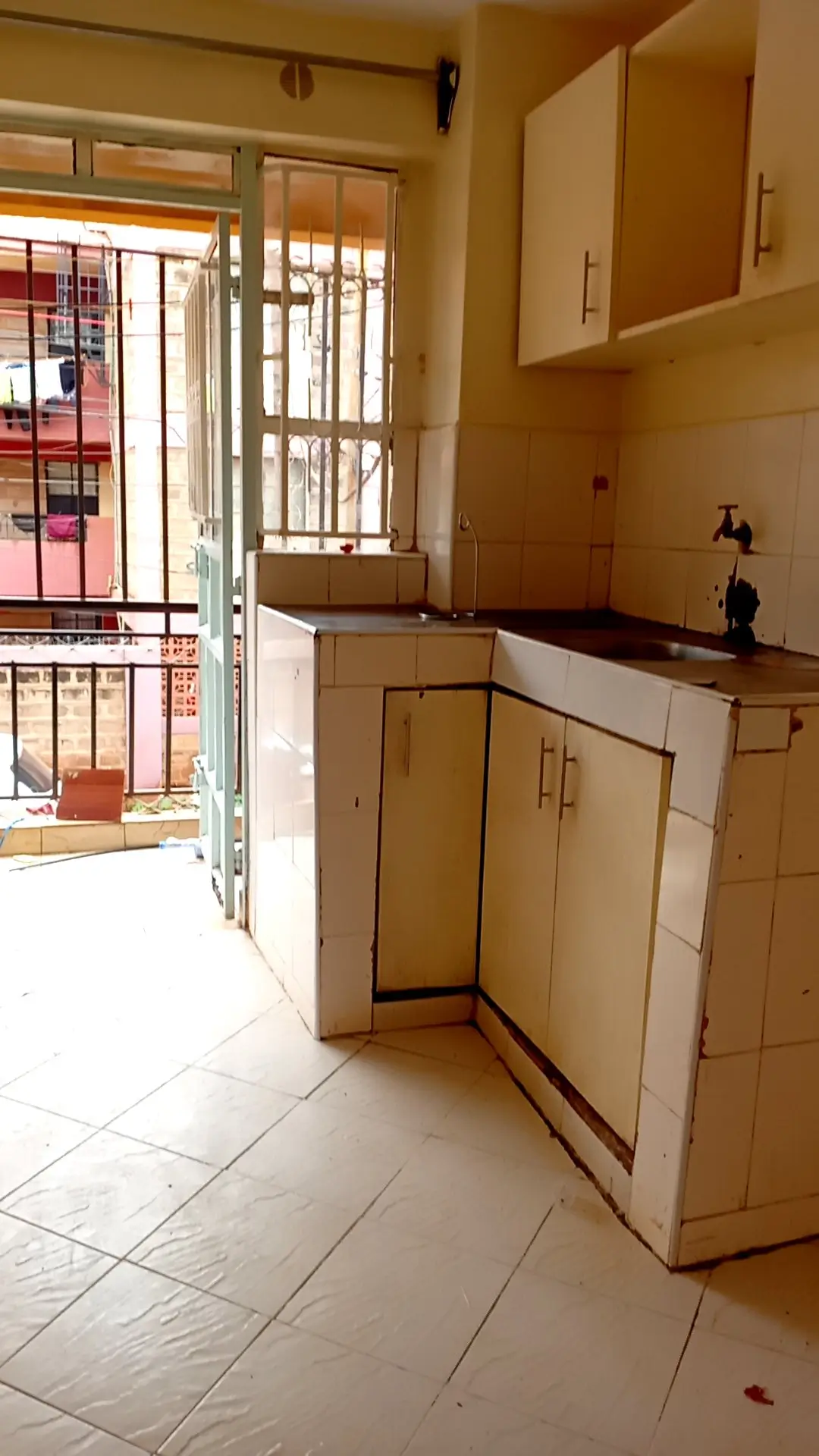 Compact kitchen with cream cabinets, balcony access visible