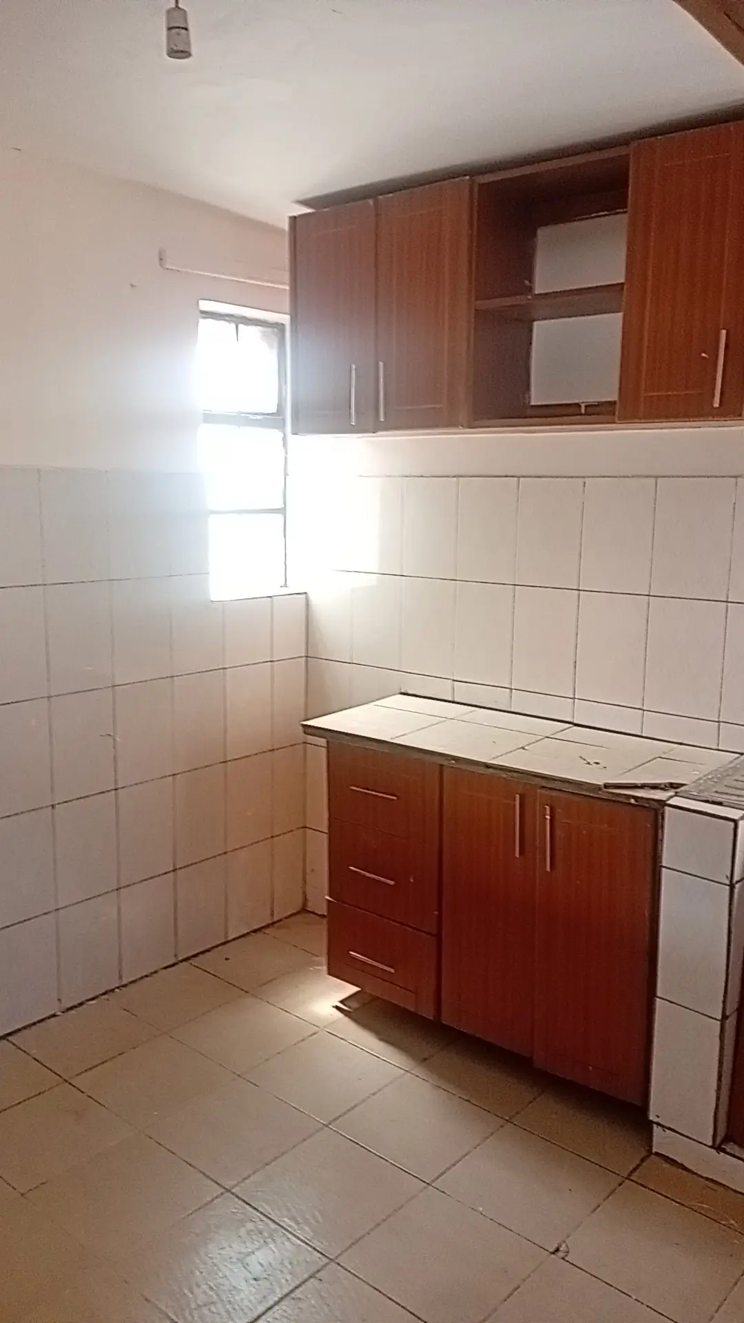 Compact kitchen with wooden cabinets and white tile walls