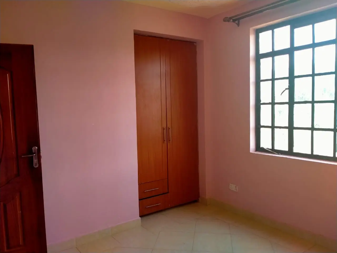 Empty bedroom with pink walls and wooden wardrobe doors