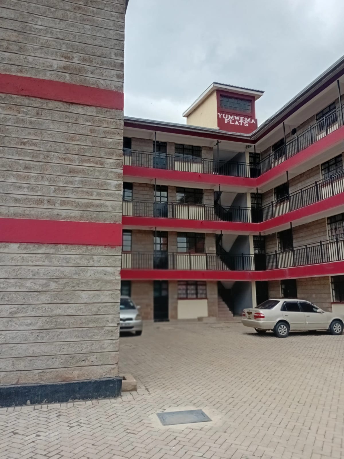 Multi-story apartment complex with red accents and ground parking