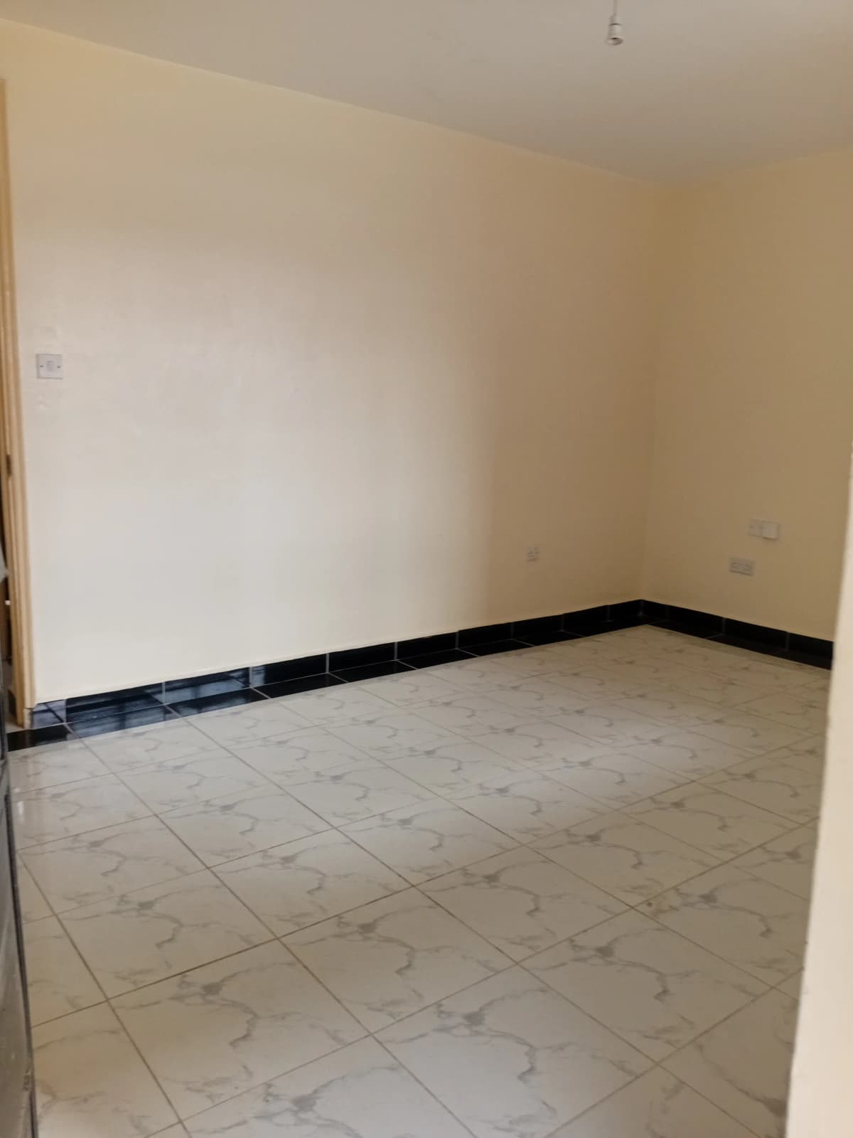 Empty room with tile flooring and black trim detail