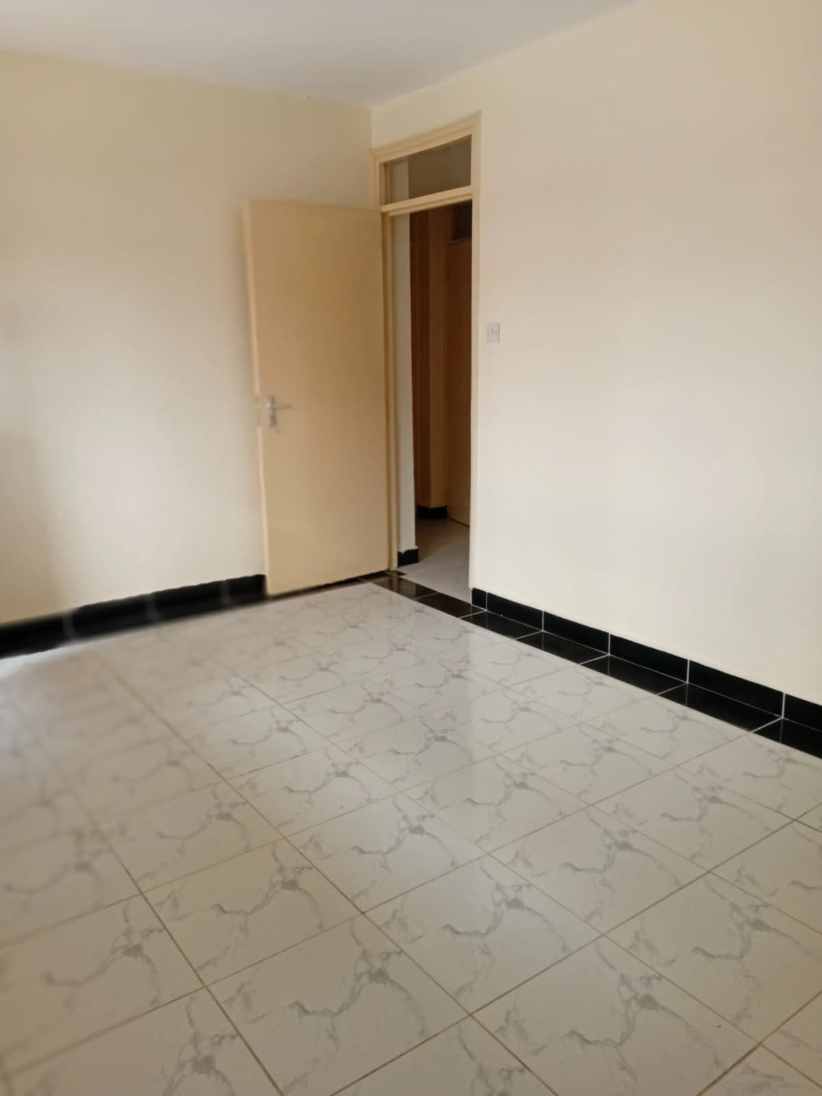 Empty bedroom with marble floor and black skirting.